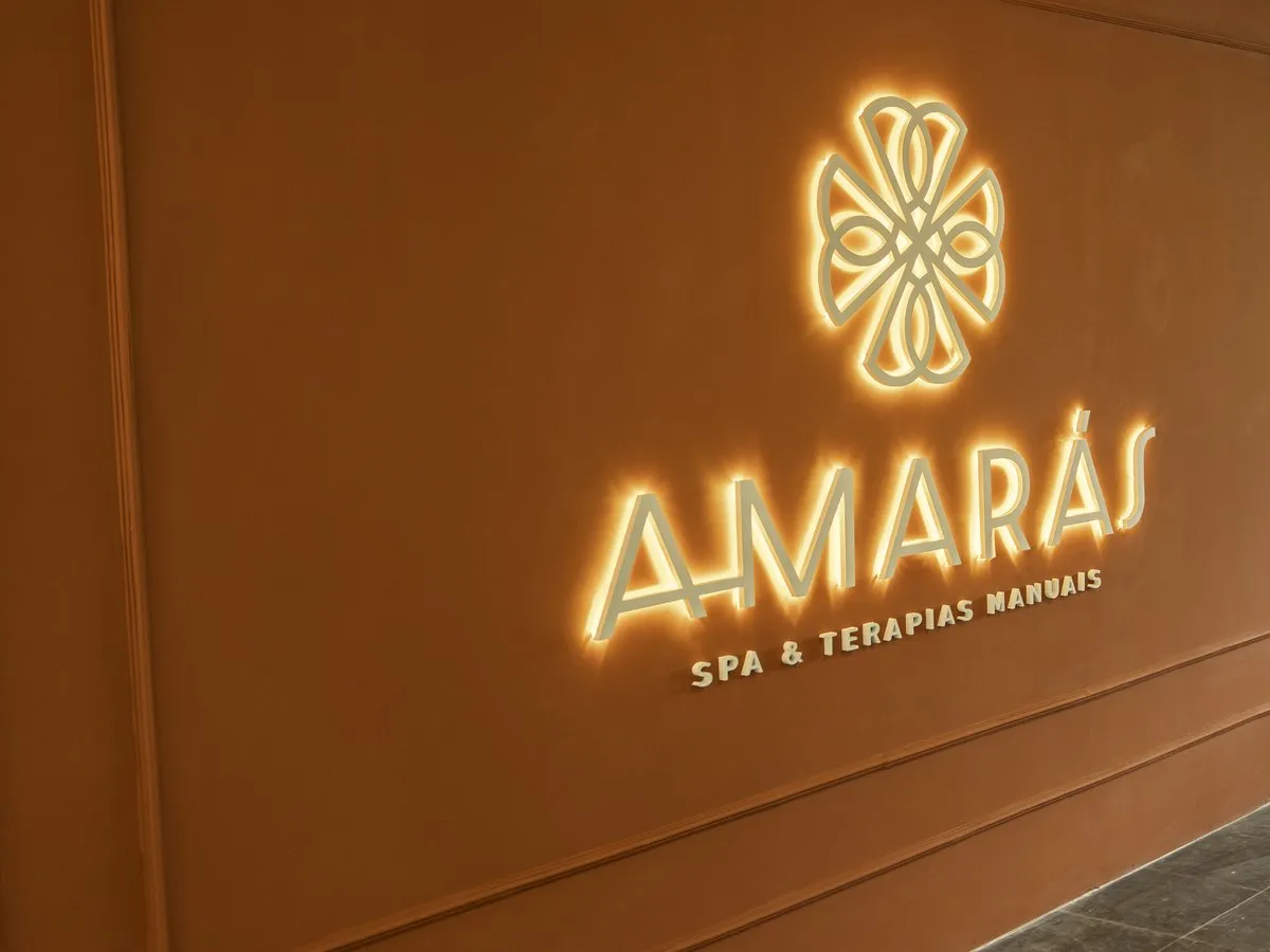 Letreiro iluminado Amarás Spa e Terapias Manuais na parede terracota da unidade