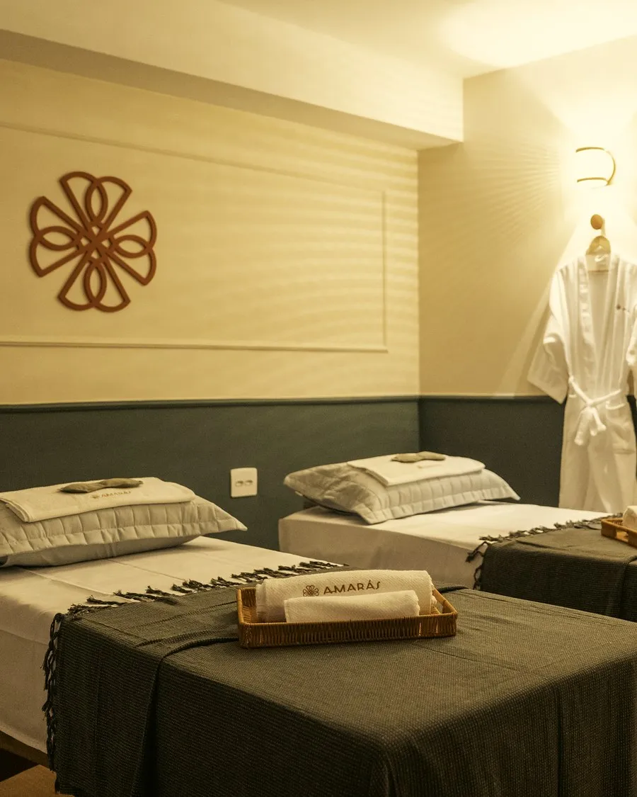 Sala dupla com duas macas, mandala na parede e roupões Amarás